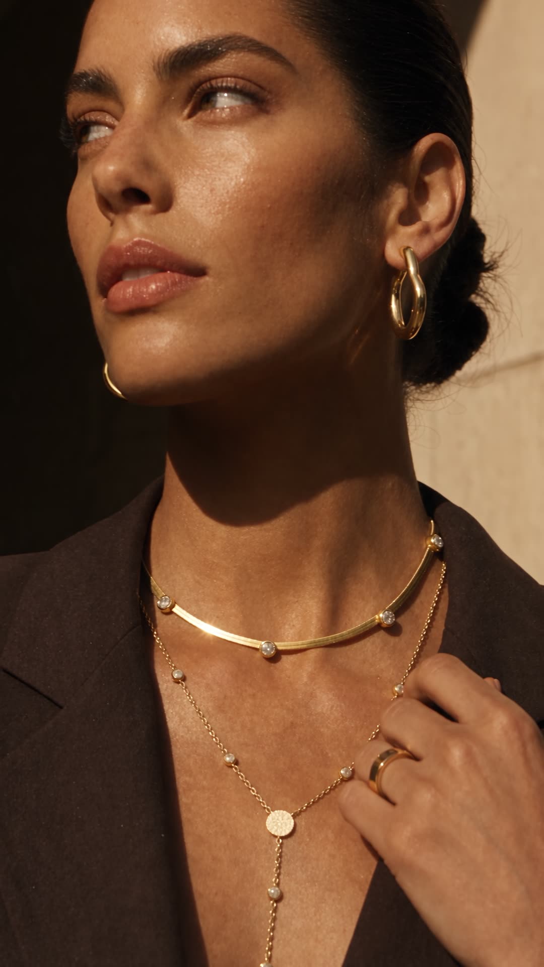 Close-up of gold-coloured jewellery worn with a dark jacket.